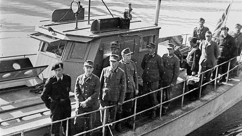 Fleire Gestapo-soldatar står oppstilt langs rekka på ein båt. Foto i svart-kvitt. - Klikk for stort bilete